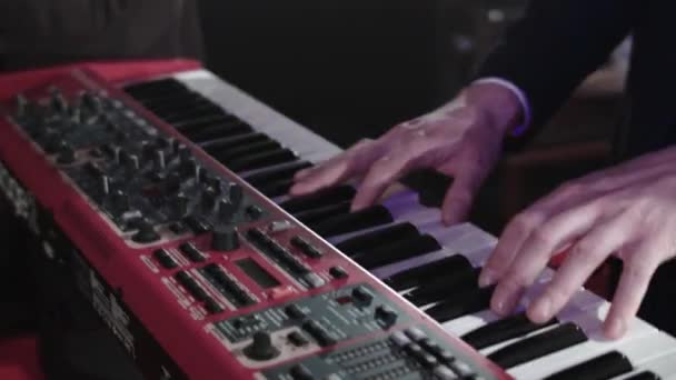 Close-up of the hands of a pianist who plays the synthesizer along with his band. Performances by a musical group at a concert in a nightclub. Musician keyboard player in a group band — Stock Video