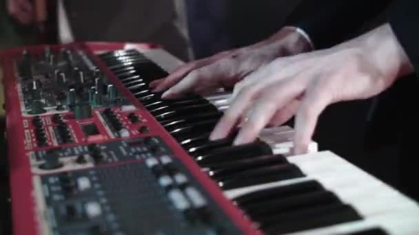 Close-up de um sintetizador tocado por um músico nos raios de luz da música. Tecladista músico em uma banda popular Performances de um grupo musical em um concerto em uma boate — Vídeo de Stock