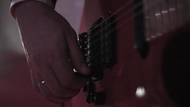 Närbild av handen på en musiker som tonar en elgitarr innan han uppträder på en konsert. Gitarristen vrider på växeln på gitarren för att förstärka ljudet. Långsam — Stockvideo