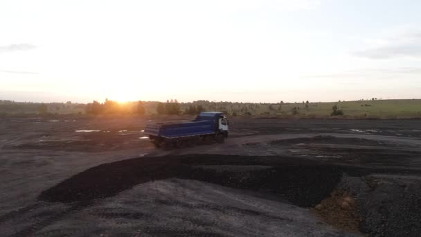 Un camion puternic se deplasează off-road în razele soarelui apusului. Un camion cu cinci axe de roți depășește calm terenul dificil cu gropi și bălți — Videoclip de stoc