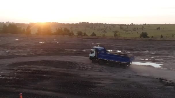 De drone vliegt rond een krachtige truck met vijf wielen die rond de steengroeve rijdt om lading te laden. Truck dump truck gemakkelijk overwint moeilijke off-road gebieden met putten — Stockvideo
