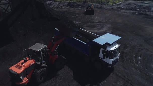 Un potente cargador de minería carga un camión volquete pesado con mineral de carbón. Primer plano de un dron cargando camiones con mineral de carbón. Cantera para minería de carbón, a cielo abierto Vídeo De Stock