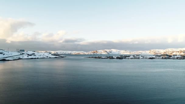 O drone voa baixo sobre a água na baía do Mar do Norte. Aldeia de pescadores na costa nevada. Clima severo dos mares do norte Península de Kola. Teriberka. Murmansk — Vídeo de Stock