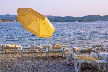 Plaj tatili kavramları. Karadağ, Tivat. Kotor Körfezi kıyısında güneşli bir sonbahar gününde sahil şemsiyesi
