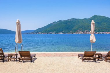 Yaz tatilleri, kumsalda güneşli bir gün. Karadağ, Adriyatik Denizi, Tivat kenti yakınlarındaki Kotor Körfezi manzarası. Metin için boşluk