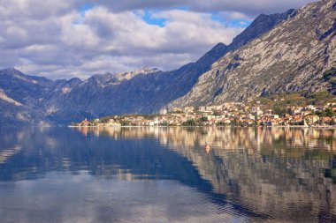 Güzel bir kış Akdeniz manzarası. Karadağ, Kotor. Dağlar ve bulutlar Kotor Körfezi 'nin suyuna yansıyor. Işık ve gölgenin zıtlıkları