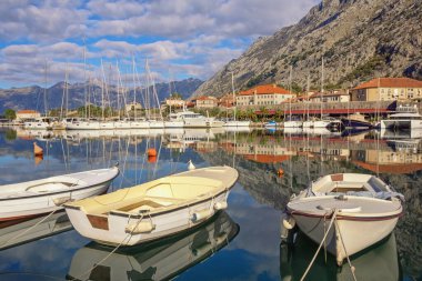 Karadağ 'da güneşli bir kış günü. Kotor Eski Kasabası yakınlarındaki Kotor Körfezi manzarası. Balıkçı tekneleri, yatlar ve şehrin kırmızı çatıları suya yansıyor.