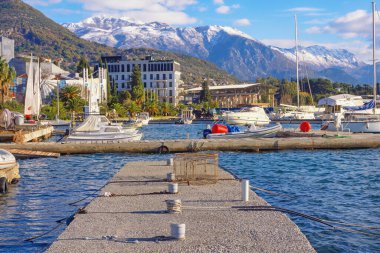 Tivat, Karadağ - 13 Aralık 2021: Kotor Körfezi manzarası ve güneşli kış gününde Lovcen dağları. Seljanovo köyü yakınlarındaki küçük marinada yatlar ve tekneler.
