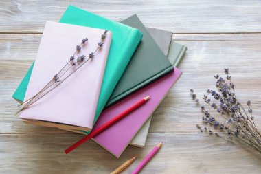 Kuru lavanta çiçekleri, renkli kalemler ve kırsal masada yığınla kitap. Boşluğu kopyala