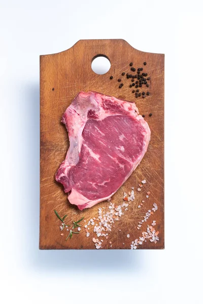 ハイファー ステーキ 牛肉だ スパイス コショウ ピンク塩 ローズマリーと木製のまな板のステーキ 木のテーブルの上で生肉 — ストック写真