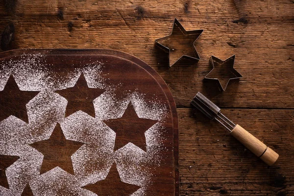 クリスマスクッキーの準備 木製のまな板にクッキーの装飾のためのアイシングシュガーと左の星型の印刷物 — ストック写真