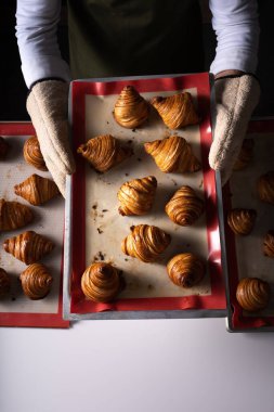 Pasta şefi taze pişmiş kruvasanları elinde tutuyor.