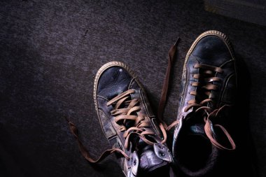 Eski kirli ve kırık ayakkabılar ve koyu arkaplanda boya damlaları.