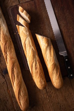 Tahta masada bıçaklı baget. İkiye bölünmüş baget. Bir dilim ekmek. Tipik Fransız ekmeği
