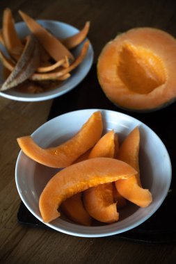 Tabak tahtasında kavun dilimleriyle. Arka planda yarım karpuz ve deri kalıntıları var.