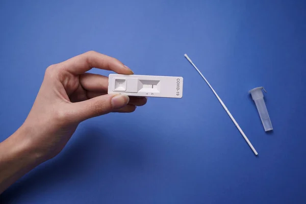 COVID-19 ile el, negatif koronavirüs testi sonucu ile hızlı test. Mavi arkaplan