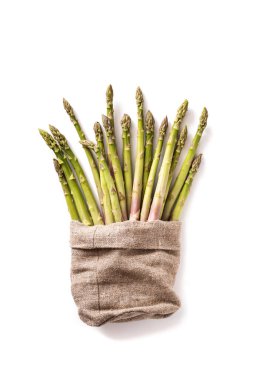 Beyaz arka planda, keten çuvalın içinde çiğ kuşkonmaz grubu.