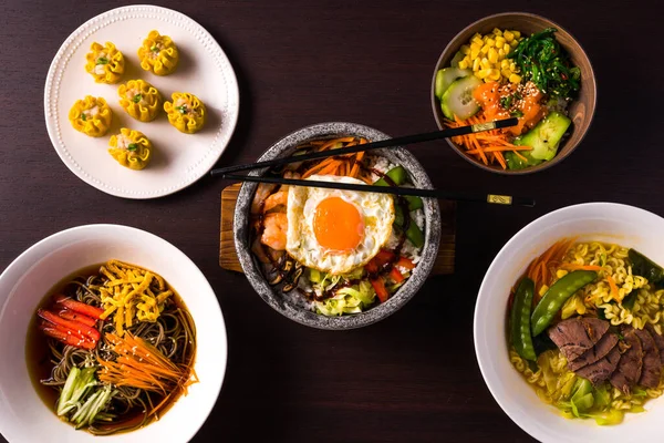 様々なアジア料理のグループエビのXiaomai ラーメン 冷たいそば ビビンバ 野菜と豚肉 水平方向の上からの眺め暗い背景 — ストック写真