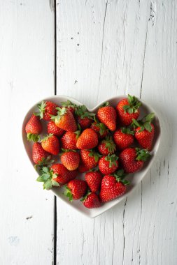 Beyaz arka planda kalp şeklindeki çilekler