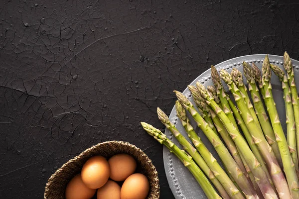 Bir tabak çiğ kuşkonmaz ve yumurta septi. koyu arkaplanda