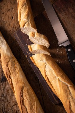 Tahta masada bıçaklı baget. İkiye bölünmüş baget. Bir dilim ekmek. Tipik Fransız ekmeği