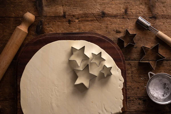 星の形をしたクリスマスクッキーの準備木製のテーブルの上に回転ピン クッキーカッターで — ストック写真
