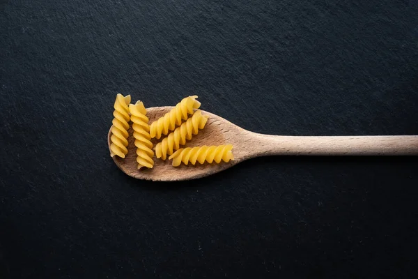 Sendok Dapur Kayu Dengan Pasta Fusilli Dengan Latar Belakang Gelap — Stok Foto