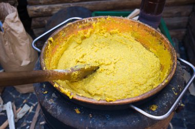 Tahta kepçeyle yemek pişirirken polentalı kazan.