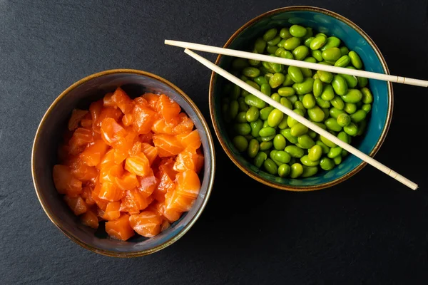 生のマグロと枝豆を箸で上にのせる 暗い背景だ 典型的なアジアの食材 — ストック写真