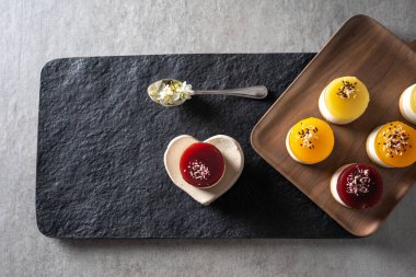 Meyve ve ricotta reçelli keklerden oluşan bir grup. Üzerinde erik çiçekleri olan gri masa üstü..