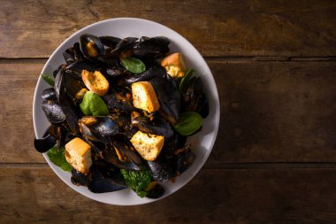 Karabiberli midye. Bir tabak midye, domates sosu ve kızarmış ekmek. Ahşap masanın üzerinde. Yukarıdan bak. Yukarıdan görüntüle. 