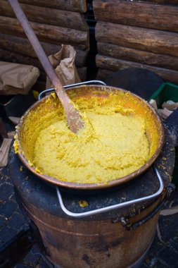 Tahta kepçeyle yemek pişirirken polentalı kazan.