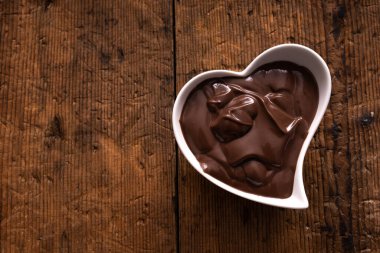 Kalp şeklinde kase çikolata kremi ile ahşap masanın üzerinde. yatay üst görünüm