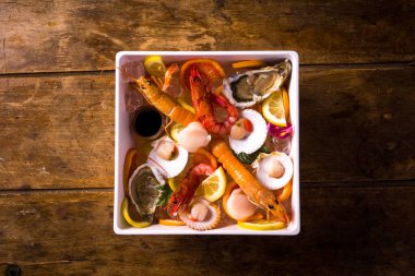 Buzlu çiğ deniz ürünleri tabağı. Karides, karides, istiridye, istiridye, canestrelli, limon ve portakal dilimlerinden oluşur. en üstteki görünüm