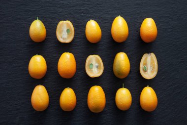 Siyah taştan bir arka planda bir grup Kumkat. Turunçgil meyvesi. Yukarıdan görüntüle.