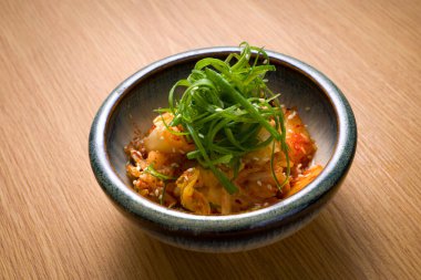 Bir kase kimçi, az baharatlı mayalanmış ve ahşap masanın üzerinde marine edilmiş Çin lahanası.