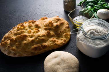 Karanlık arka planda hazırlanmak için malzeme ve hamur içeren Roma Focaccia 'sı
