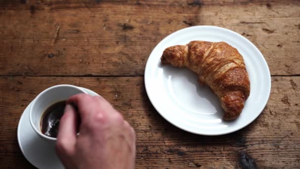 コーヒーとクロワッサンで朝食を 口にクロワッサンを持ってきて — ストック動画