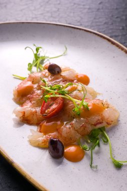 Terbiye edilmiş karides kuyruklu yemek, vişneli domates, zeytin ve mangolu mus. Karanlık arka plan. detay