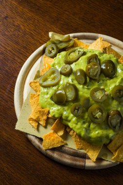 Tahta masanın üzerinde Guacamole ve tortilla cipsi tabağı. Tipik Meksika yemeği. detay