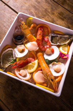 Buzlu çiğ deniz ürünleri tabağı. Karides, karides, istiridye, istiridye, canestrelli, limon ve portakal dilimlerinden oluşur. detay