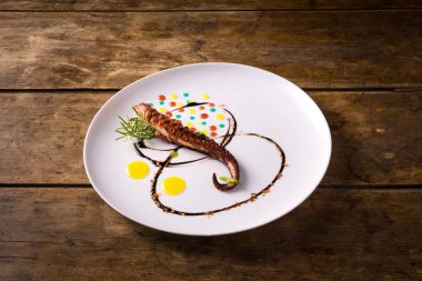 Renkli soslu ızgara ahtapot tabağı. Ahşap masanın üzerinde. 