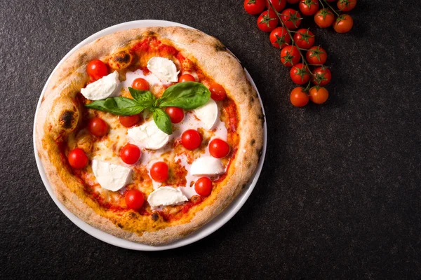 Bufalo mozzarella ve vişneli domatesli pizza. Üst görünüm siyah mermer arkaplan