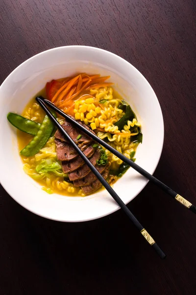 典型的なアジア料理 野菜とラーメン 麺と牛肉 暗い背景にプレート — ストック写真