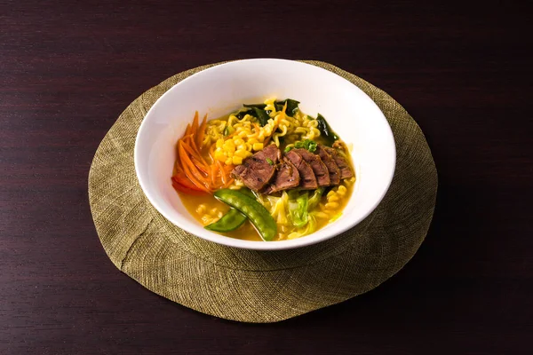 典型的なアジア料理 野菜とラーメン 麺と牛肉 暗い背景にプレート — ストック写真