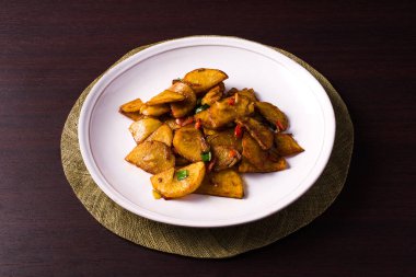 Koyu ahşap masanın üzerinde tuzlu ve biberli patates tabağı.. 