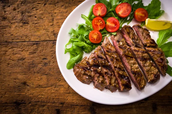 鉄板の上にトマトとサラダ付きの焼き肉ステーキ — ストック写真