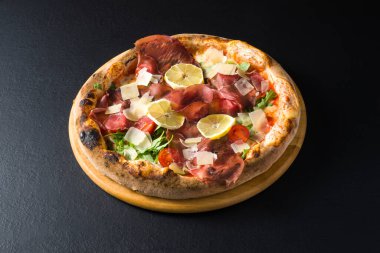 Domuz etli pizza, domates, peynir gevreği, salata ve limon dilimleri.