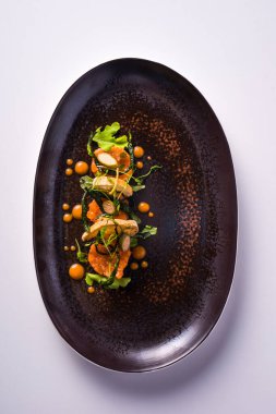 Somon tartar, kızarmış ekmek, sotelenmiş kabak ve kapari çiçekli yemek.