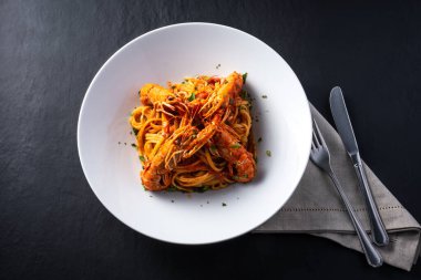 Koyu arkaplanda karidesli Busara spagettisi tabağı.